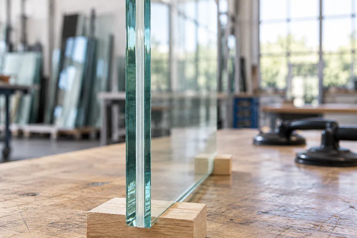 Tranche d&rsquo;un panneau de verre feuilleté avec son film intercalaire, posé sur des cales en bois